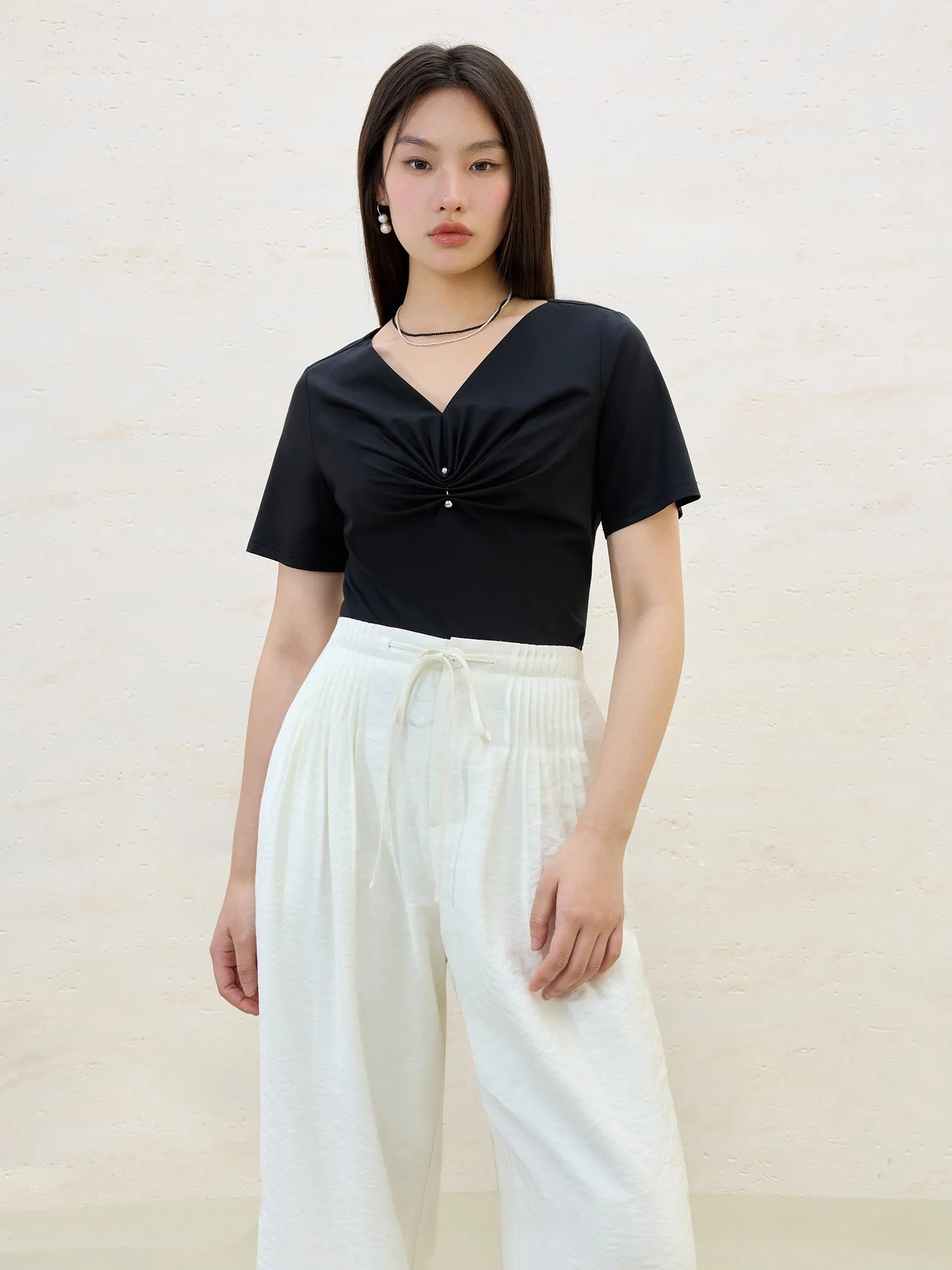 Damen-T-Shirt aus Baumwolle mit V-Ausschnitt und kurzen Ärmeln in vier Farben, mit Falten-Design an der Schulter.