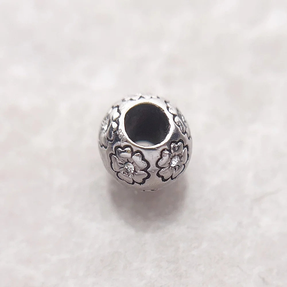 Charm-Perle aus 925er Sterlingsilber mit Blumenrelief und dunklem runden Einsatz