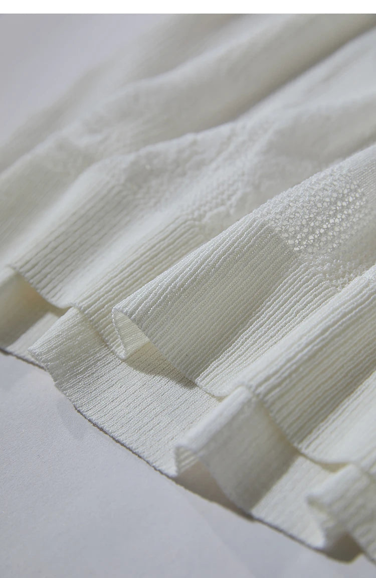 Beiger Strickpullover mit V-Ausschnitt und Halbarm; feines Lochmuster im Detail.