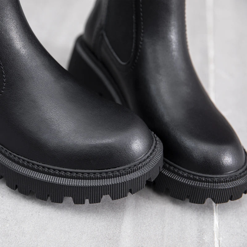 Schwarze Chelsea-Boots aus Leder, Detail der Profilsohle und elastischen Seite