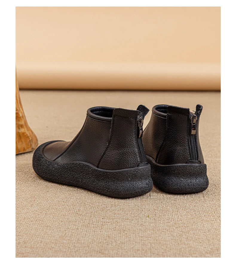 Schwarze flache Stiefeletten aus Leder mit Rundkappe und seitlichem Reißverschluss.