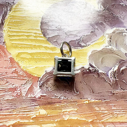 Quadratischer Anhänger mit blauem Stein, silbernes Metallgestell, offen blickend