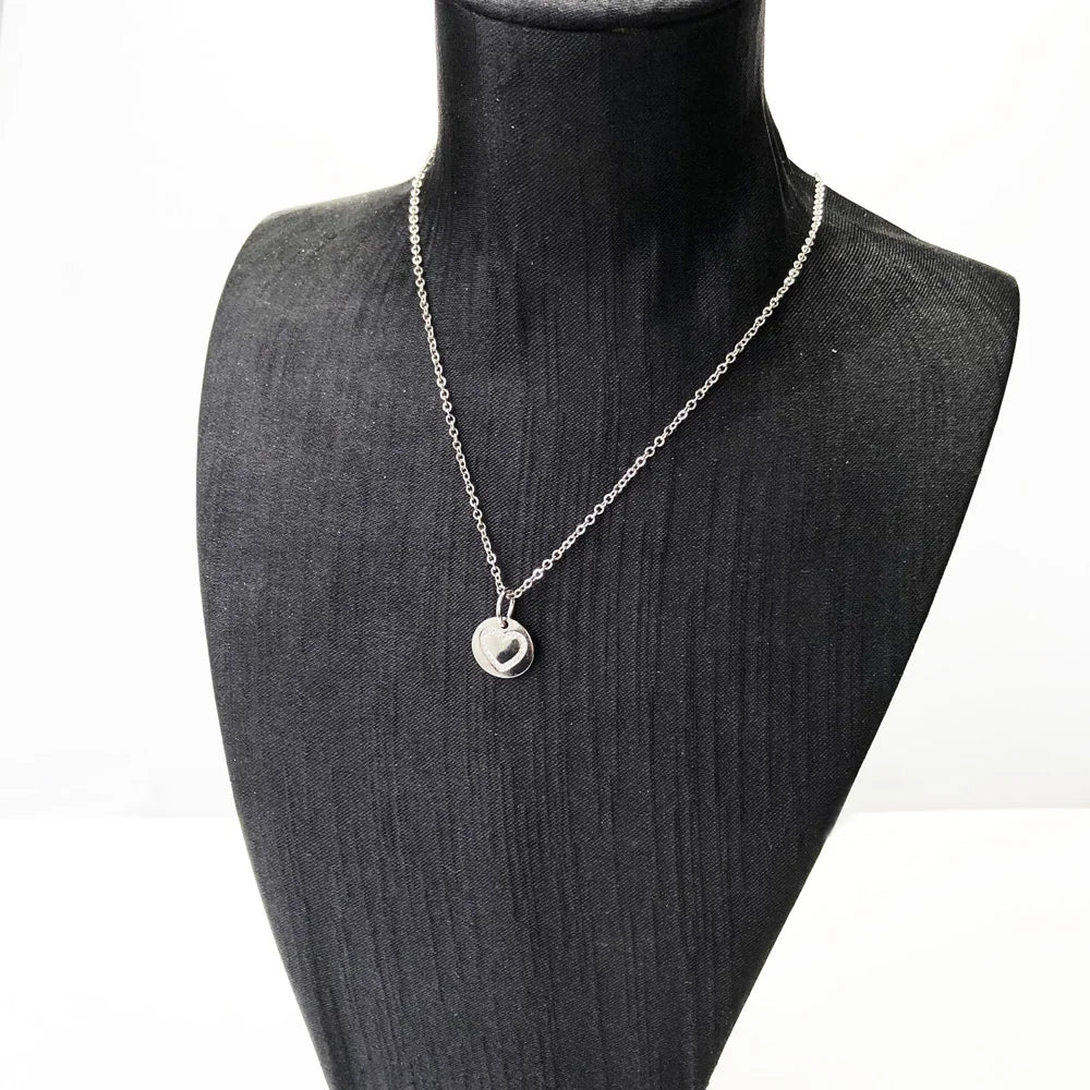 Herz-Anhänger aus Silber an Kette auf Schmuckständer, rundes Medaillon mit Herzmotiv