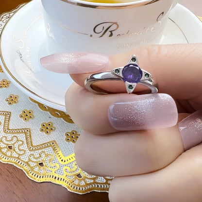 Am Finger: silberner Ring mit violettem Stein und grünen Verzierungen