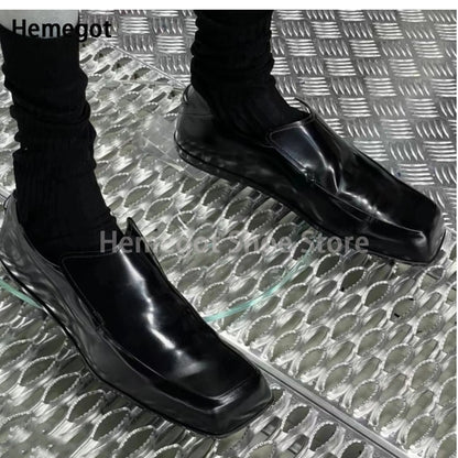 Schwarze Lederschuhe mit eckiger Spitze und flachem Slip-On, seitliche Ansicht.