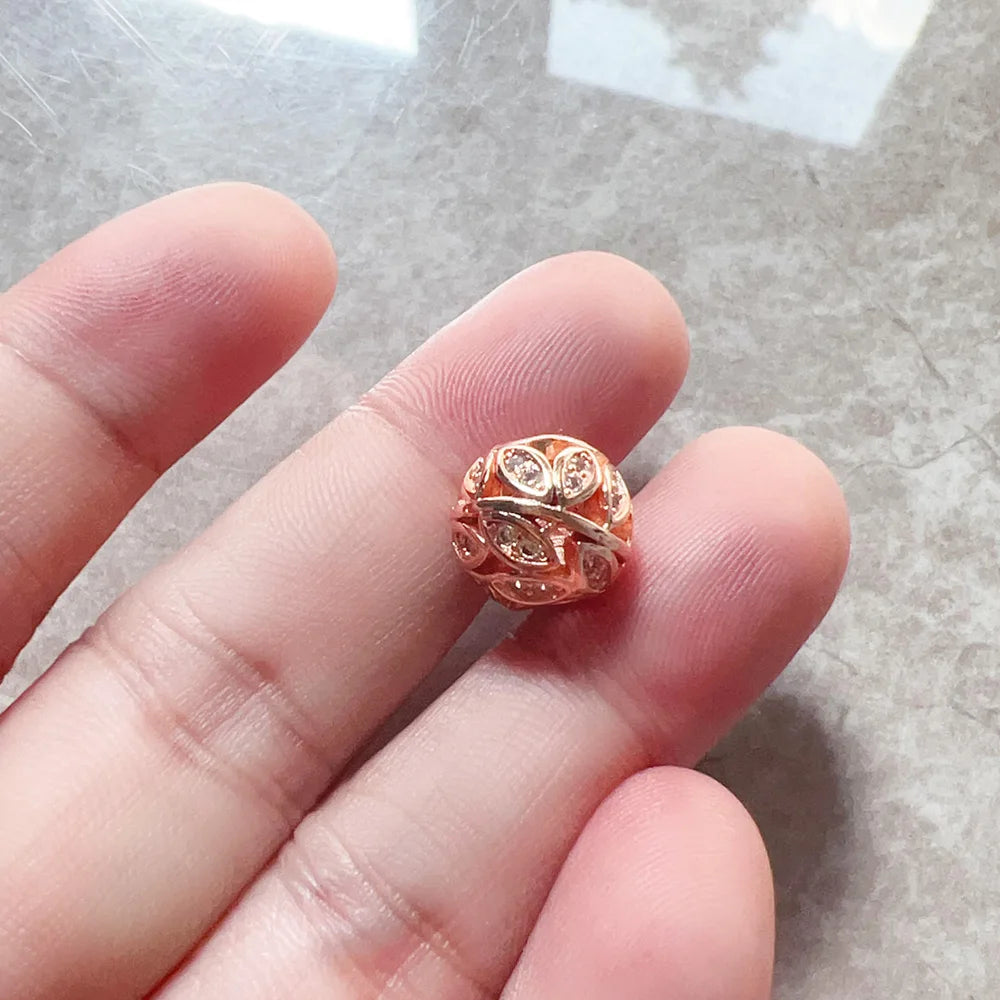 Roségoldener Charm auf Finger, mit filigranem Muster und funkelnden Steinen