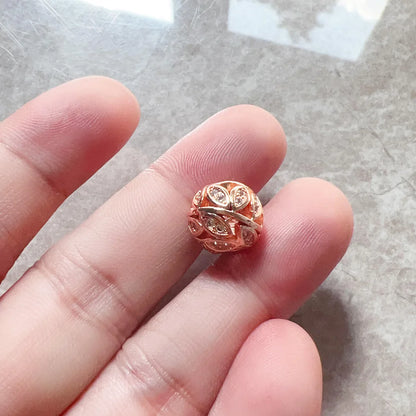 Roségoldener Charm auf Finger, mit filigranem Muster und funkelnden Steinen