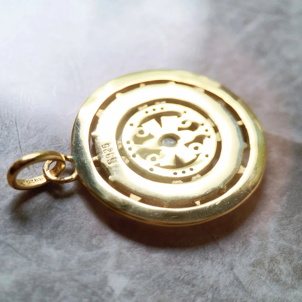 Goldfarbener runder Anhänger von hinten mit eingraviertem Symbol und befestigter Öse