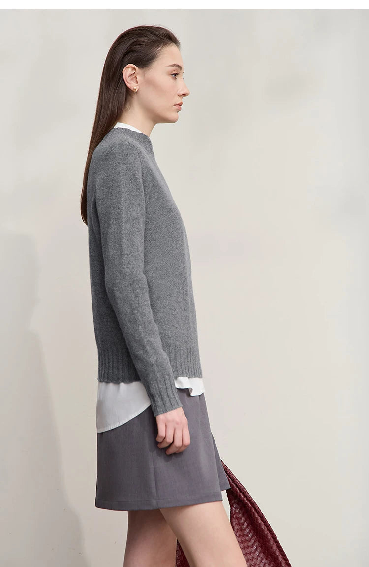 Grauer Pullover für Damen, lange Ärmel und gerippter Saum, weißer Stoff am unteren Rand.