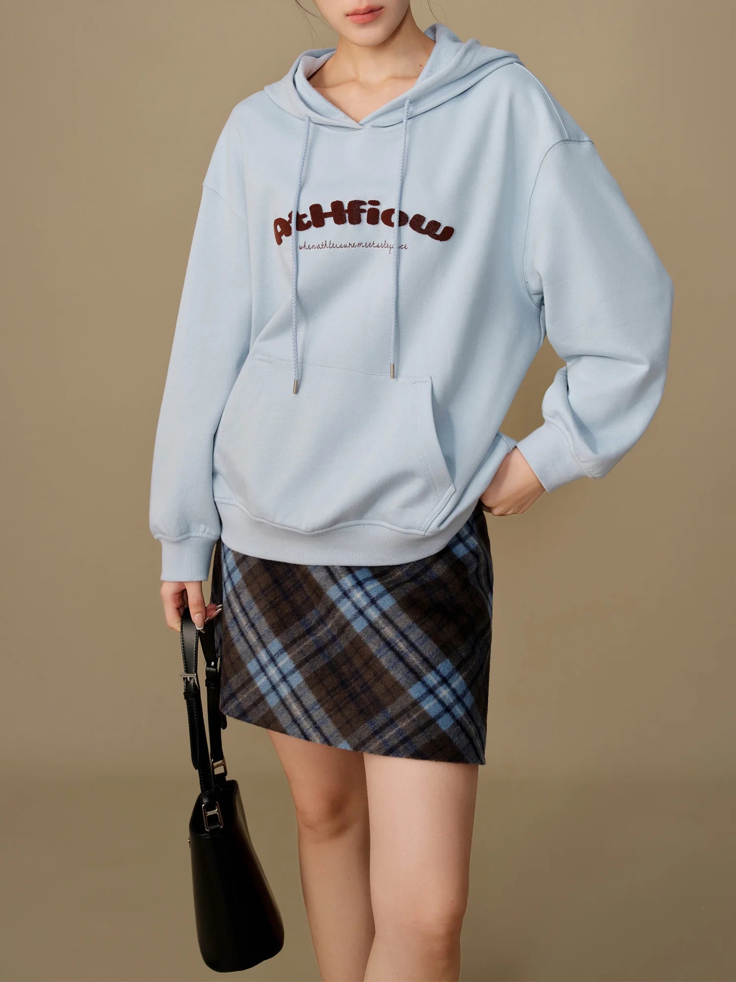 Hellblauer Hoodie mit Kapuze und Frontprint, dazu kariertes Minirock-Outfit.