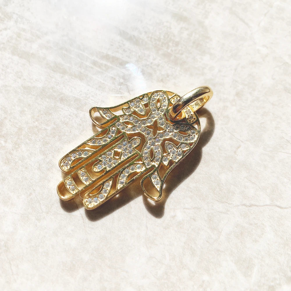 Goldfarbener Anhänger Hand von Fatima mit Strassbesatz, seitlich auf hellen Untergrund