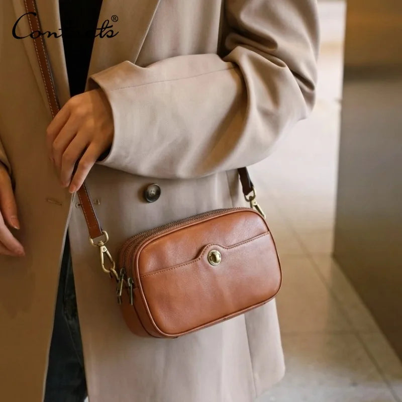 Kleine Ledertasche mit Front-Knopfverschluss und Reißverschlussfach, getragen am Schulterriemen