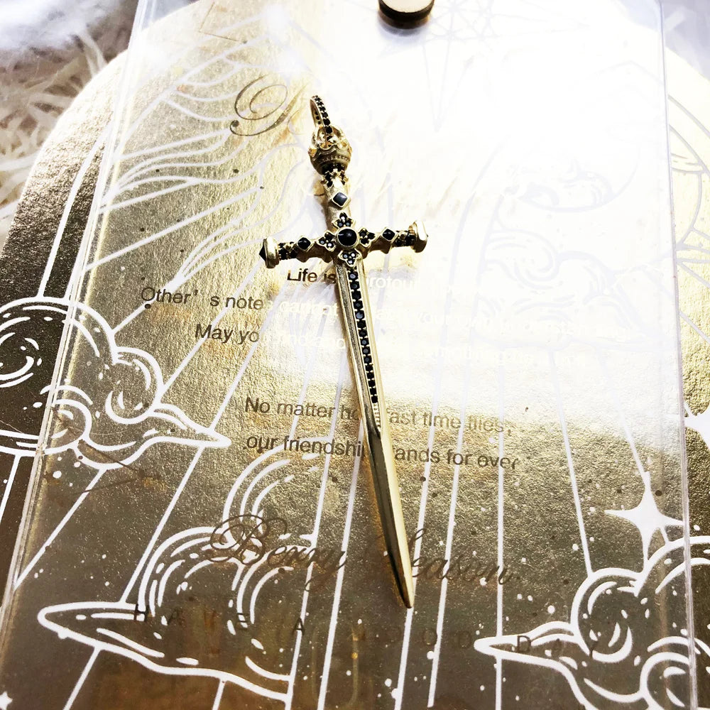 Schwert-Anhänger mit goldfarbener Oberfläche und schwarzen Ziersteinen, Detailansicht