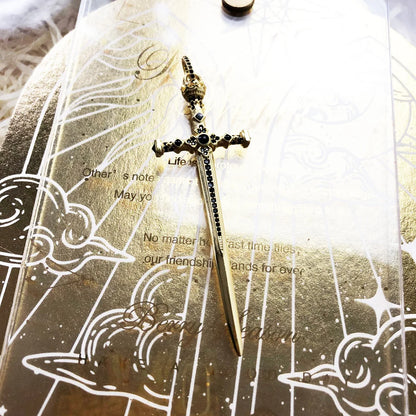 Schwert-Anhänger mit goldfarbener Oberfläche und schwarzen Ziersteinen, Detailansicht