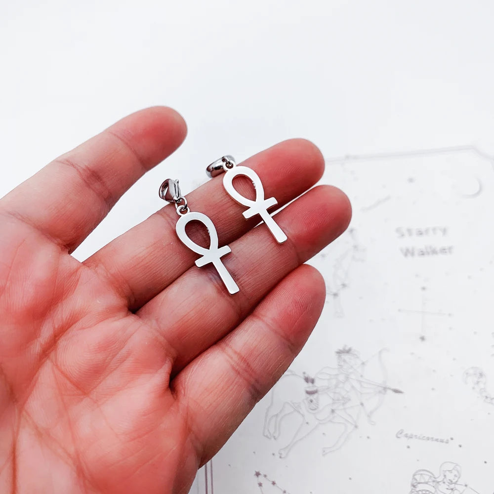 Ankh-Ohrringe aus silberfarbenem Metall an Karabinern, in Hand gehalten