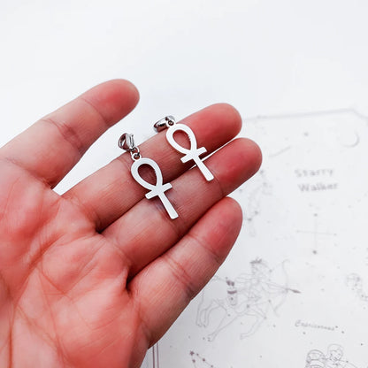Ankh-Ohrringe aus silberfarbenem Metall an Karabinern, in Hand gehalten