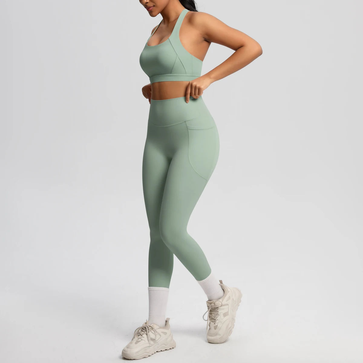 Yoga-Set: grünliches Sport-Top mit breitem Träger und Leggings mit Knöchelbund