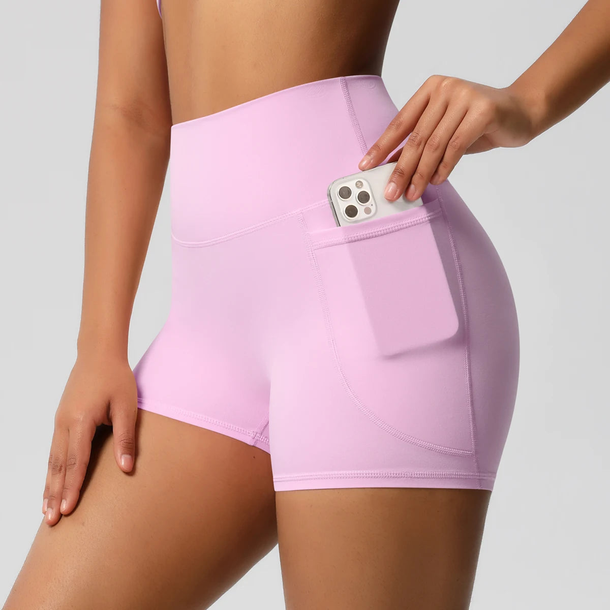 Damen-Yogashorts hohe Taille mit Seitentaschen, hellrosa, mit eingestecktem Handy