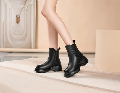 Schwarze Chelsea-Boots am Bein getragen, mit elastischem Seiteneinsatz und Blockabsatz