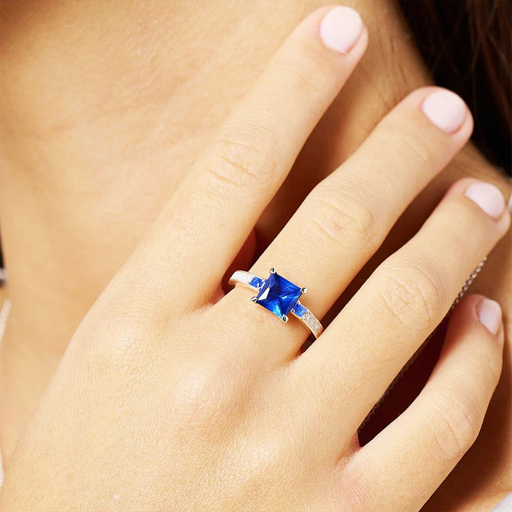Silberner Cocktailring mit quadratischem blauem Stein, Detailaufnahme am Finger