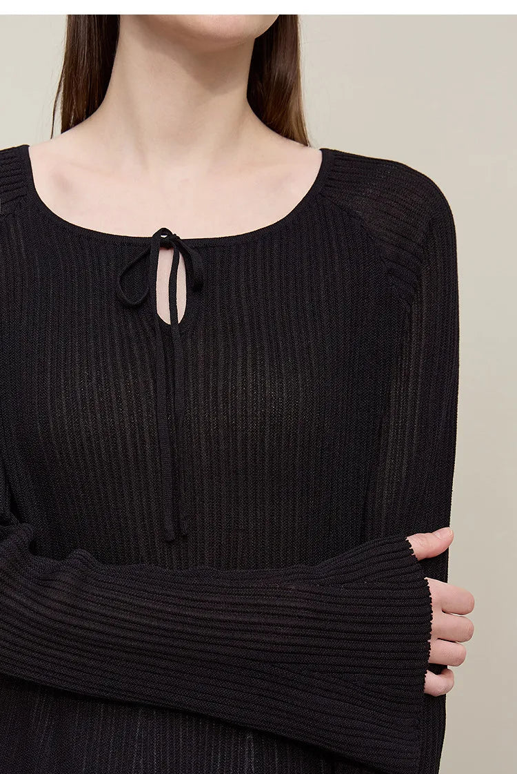 Schwarzer Rippenstrickpullover mit Rundhalsausschnitt und Schleifen-Bindekordel vorne, Detail.