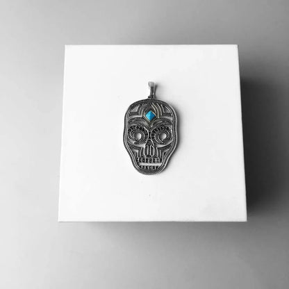 Totenkopf-Anhänger in Sterlingsilber mit blauem Stein, auf Verpackung liegend