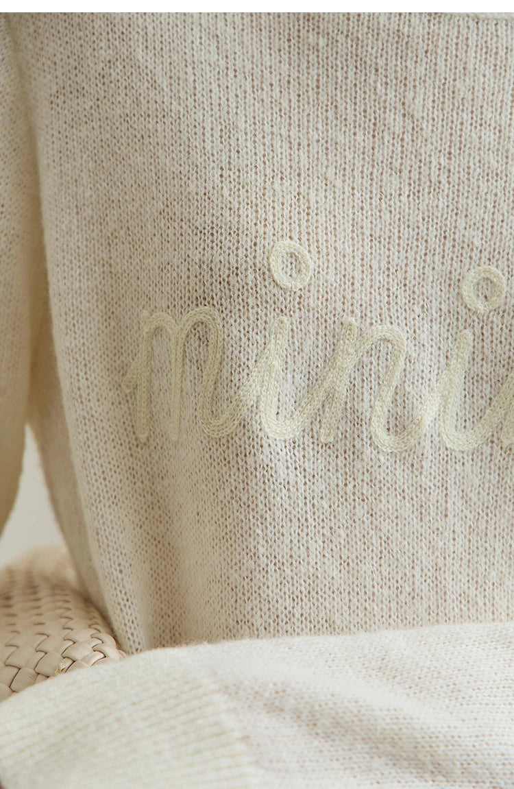 Damenpullover cremefarben im Detail: feiner Strick mit dezenter Schrift am Vorderteil