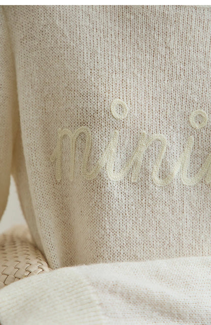 Damenpullover cremefarben im Detail: feiner Strick mit dezenter Schrift am Vorderteil