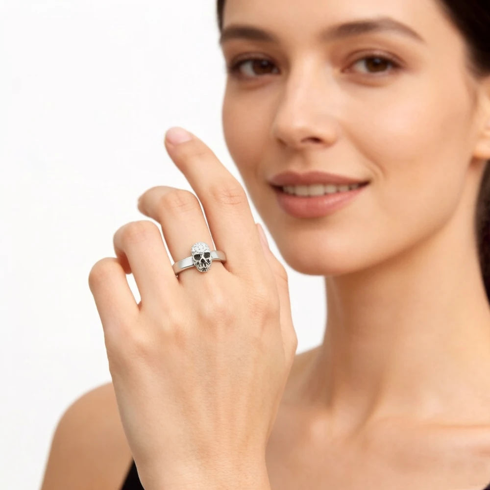 Totenkopf-Ring am Finger, silbernes Band mit Kopfmotiv, Hand in Nahansicht