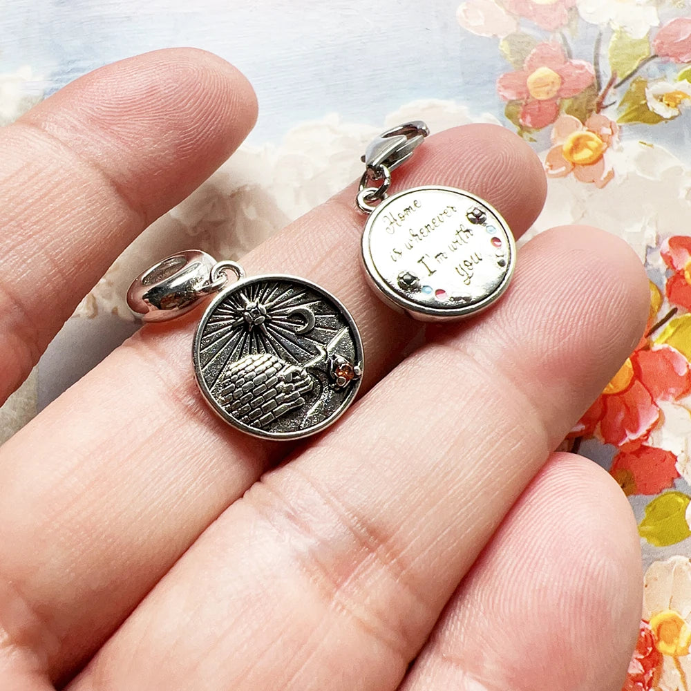 Nahaufnahme: zwei Silber-Charms mit Iglu-Motiv, innen Emaille-Akzente und Öse