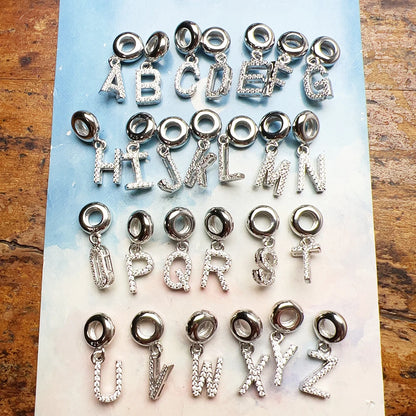 Buchstaben-Charm-Anhänger im Set: A, B, C, D und weitere, silberfarben mit Steinen