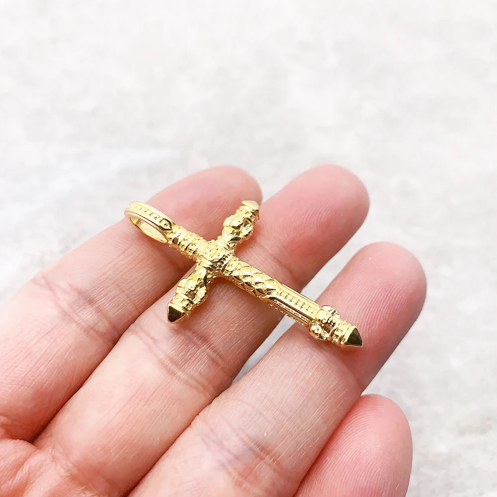 Goldener Kreuz-Anhänger in Hand gehalten, Totenkopf-Relief, dunkle Akzente an den Enden