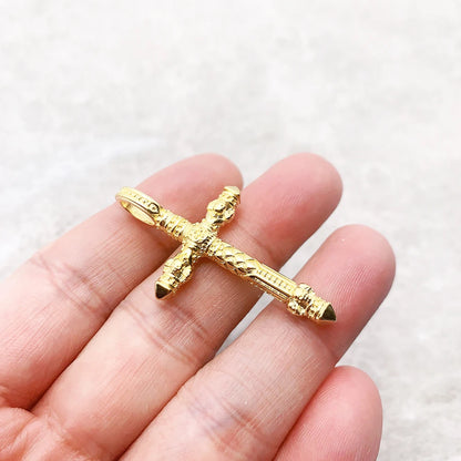 Goldener Kreuz-Anhänger in Hand gehalten, Totenkopf-Relief, dunkle Akzente an den Enden