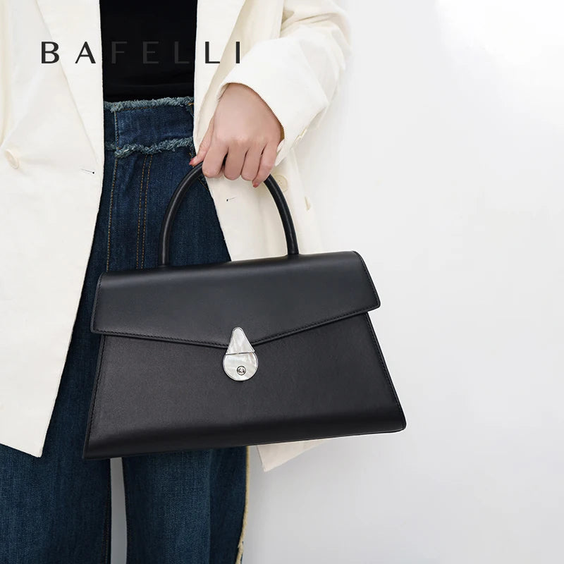 Schwarze Echtleder-Handtasche mit Schulterriemen und Klappenverschluss, getragen am Handgelenk
