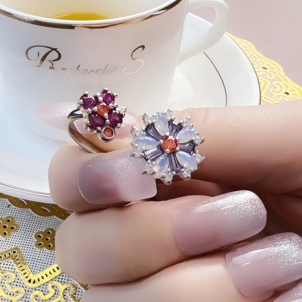 Blumenring am Finger: violette Steinblüte mit klaren Strahlen, silberfarbene Fassung