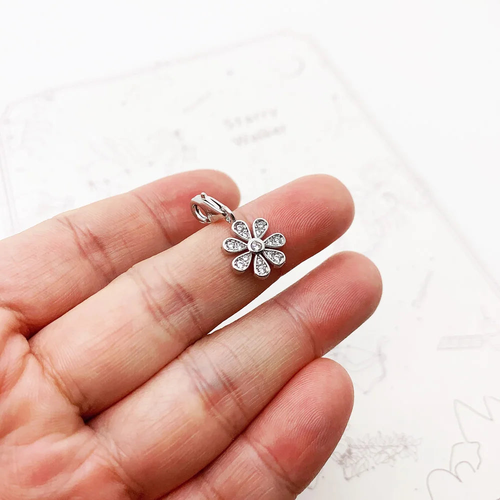 Blumenförmiger Silber-Charmanhänger mit Zirkonia, in Handfläche gehalten