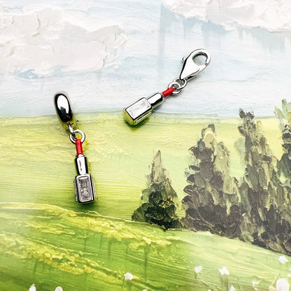 Zwei silberne Charm-Anhänger mit rotem Lippenstift-Detail und Karabinern