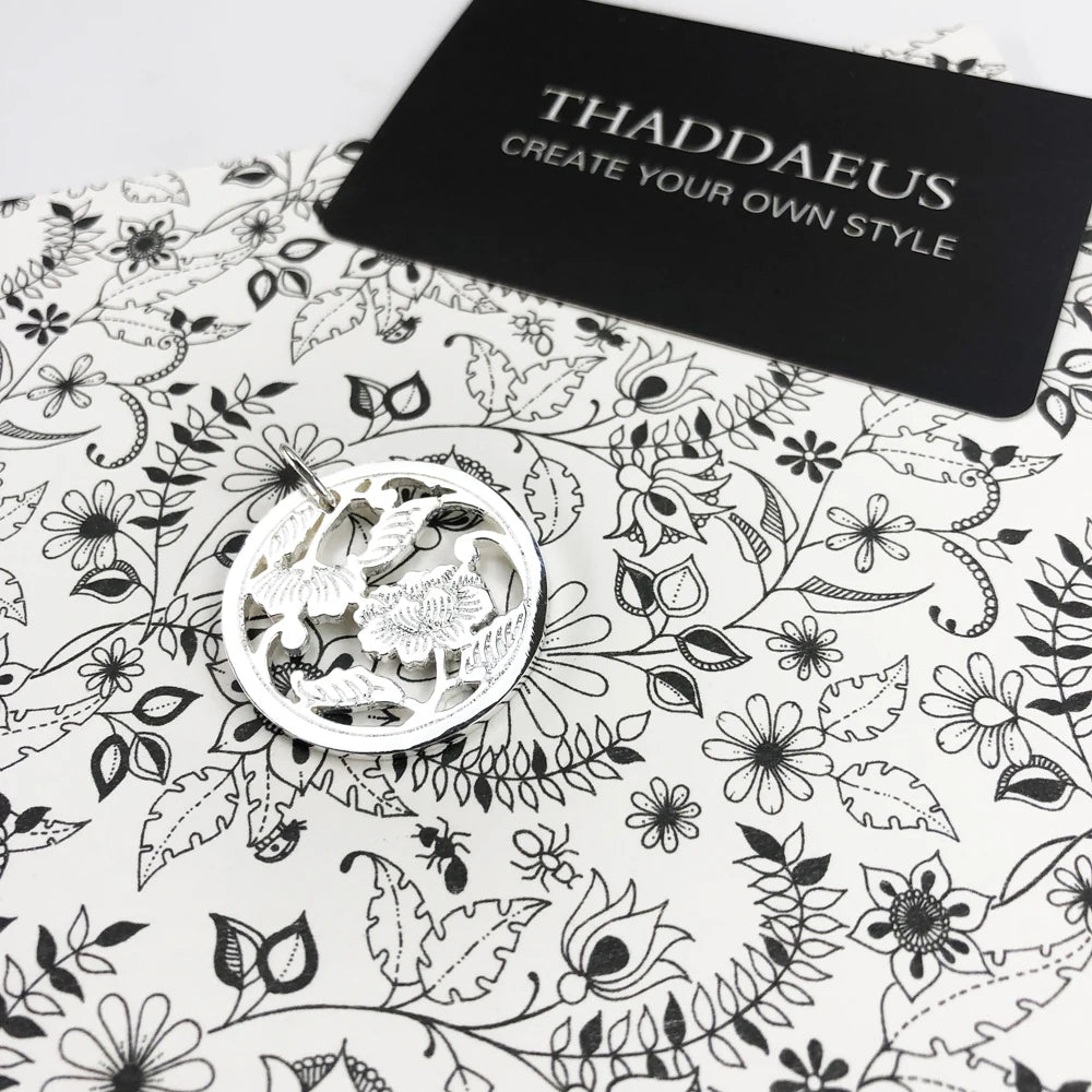 Runder Anhänger aus Sterlingsilber mit Blumenrelief, auf weißer Schmuckverpackung