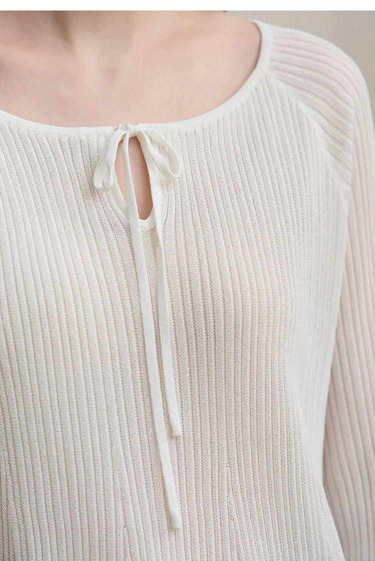 Weißer Rippenstrickpullover mit Rundhalsausschnitt und Bindekordel, Detail am Halsausschnitt.