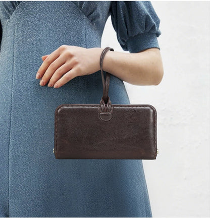 Dunkelbraune Damen-Leder-Handgelenktasche mit kurzer Schlaufe und breitem Frontbereich.