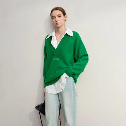 Grüner Strickpullover mit V-Ausschnitt, weißem Hemdkragen darunter, lange Ärmel.