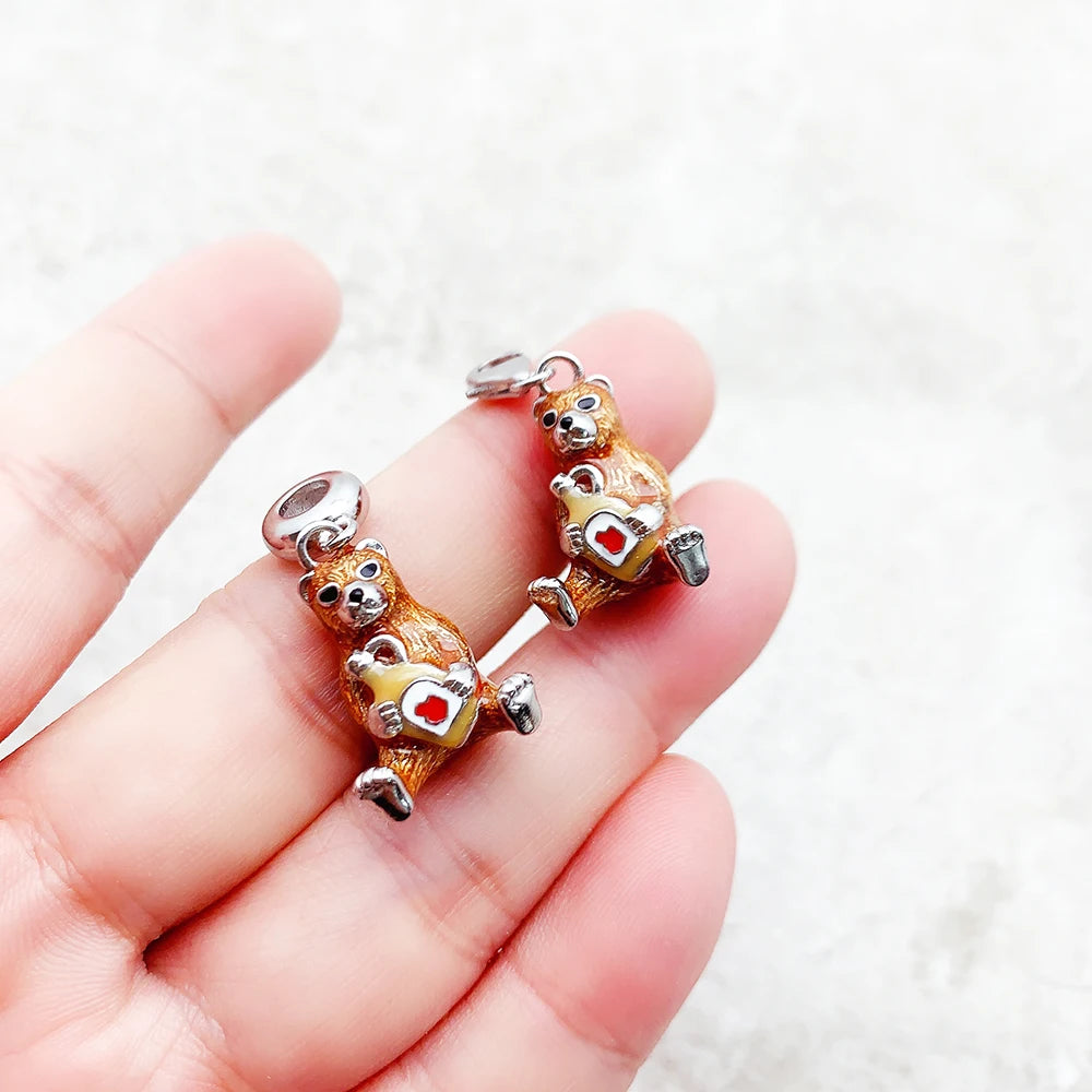 Zwei Bär-Charm-Anhänger in der Hand, 925 Silber mit rotem Herz und Öse