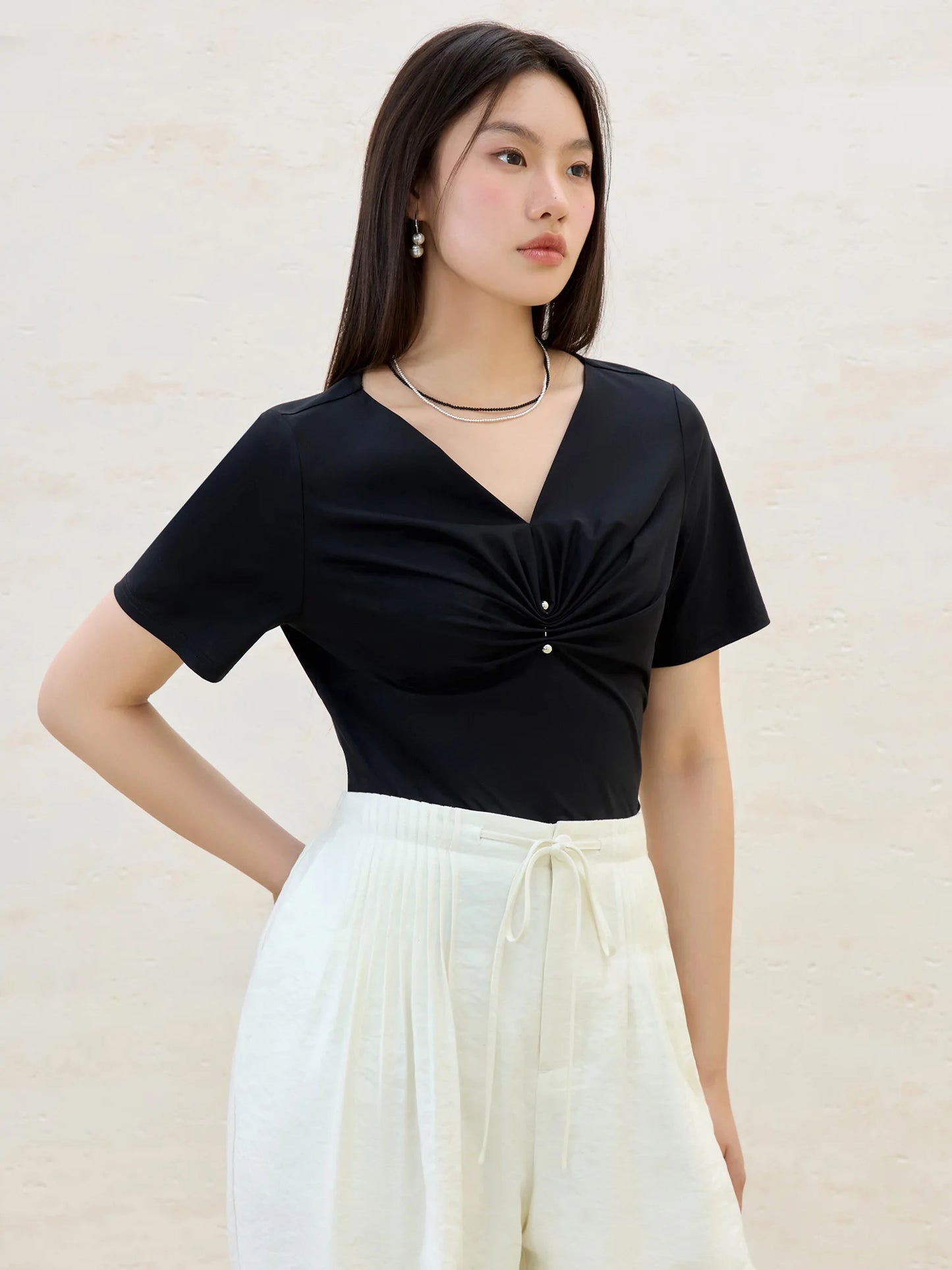 Damen-T-Shirt aus Baumwolle mit V-Ausschnitt und kurzen Ärmeln in vier Farben, mit Falten-Design an der Schulter.