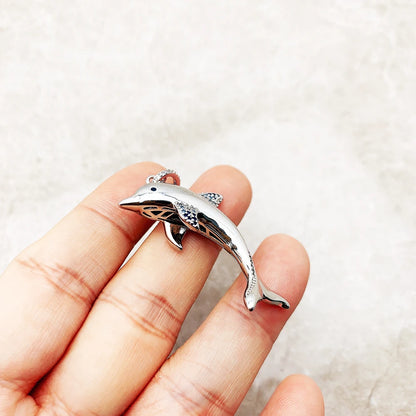 Delphin-Anhänger aus 925 Sterlingsilber in der Hand, mit blauem Steinbesatz
