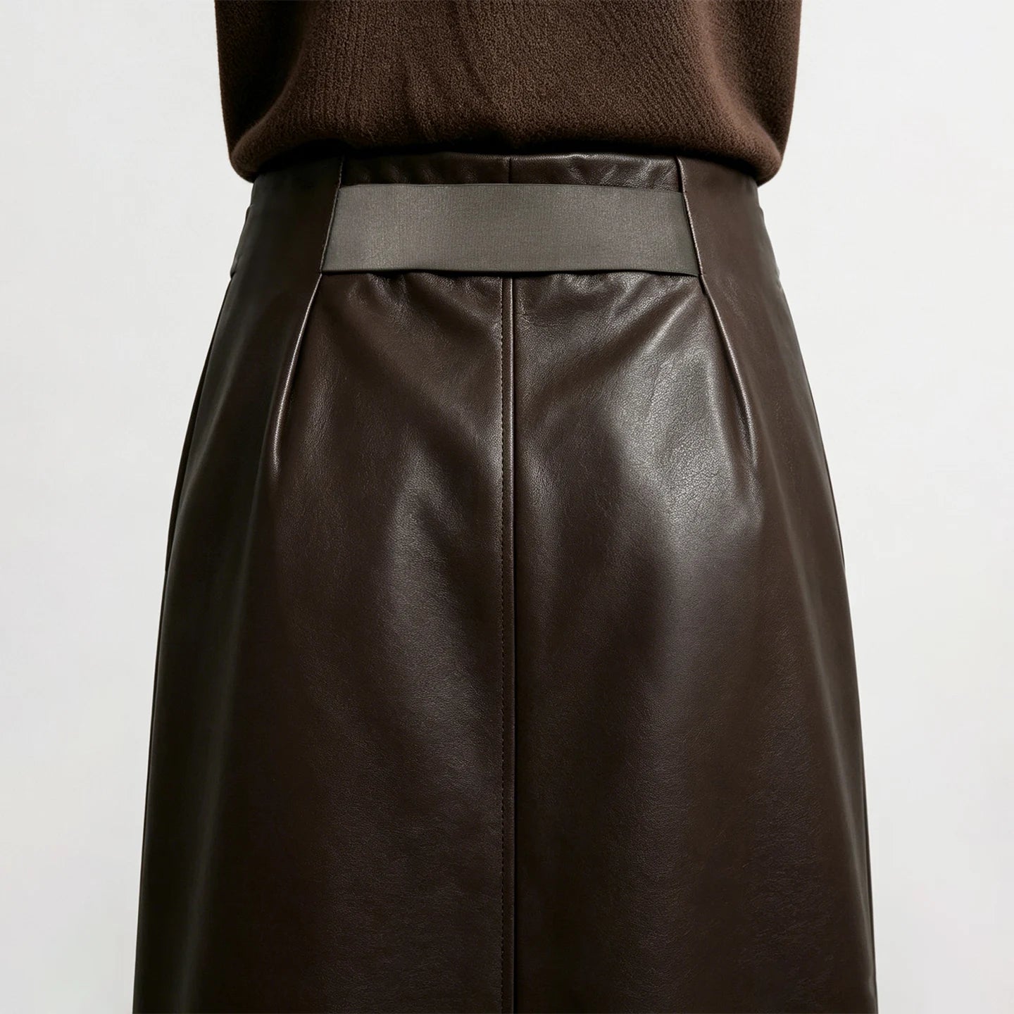 Nahaufnahme: Midi-Rock aus dunkelbraunem Kunstleder mit elastischem Bund und Mittelnaht