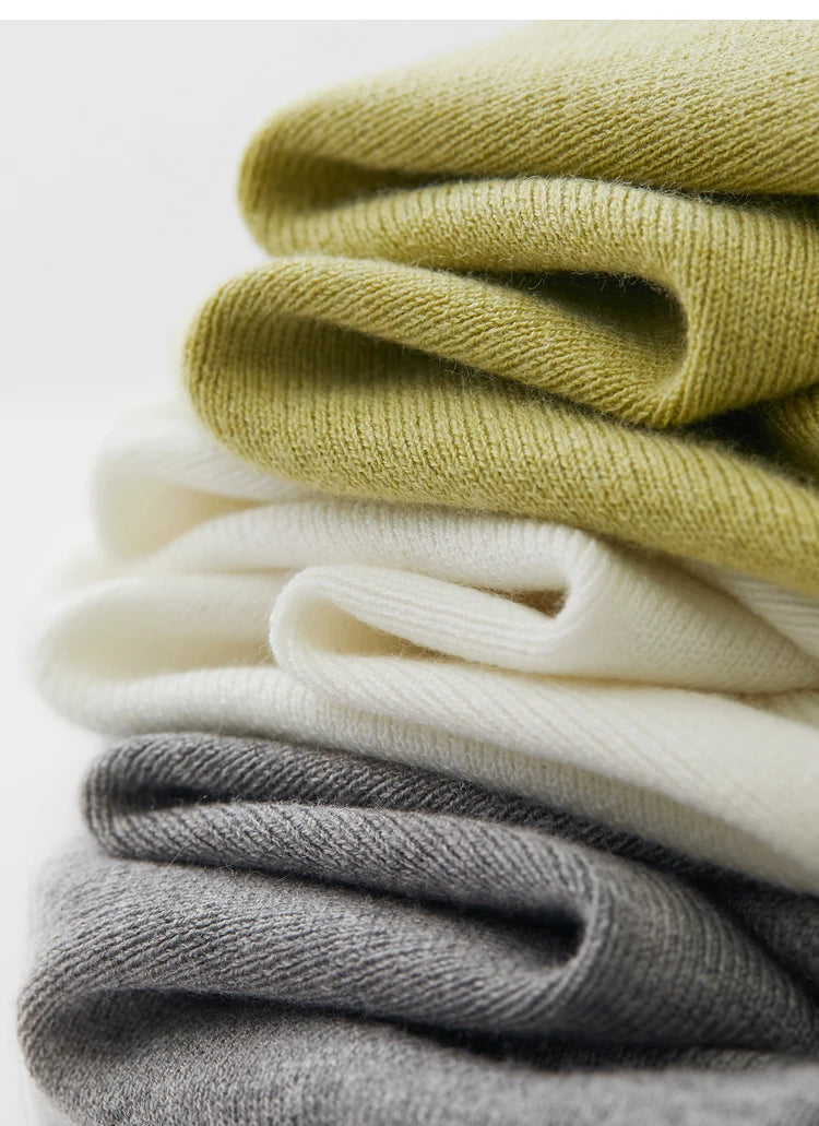 Gestapelte Strickpullover, hellgrün, weiß und grau, lange Ärmel