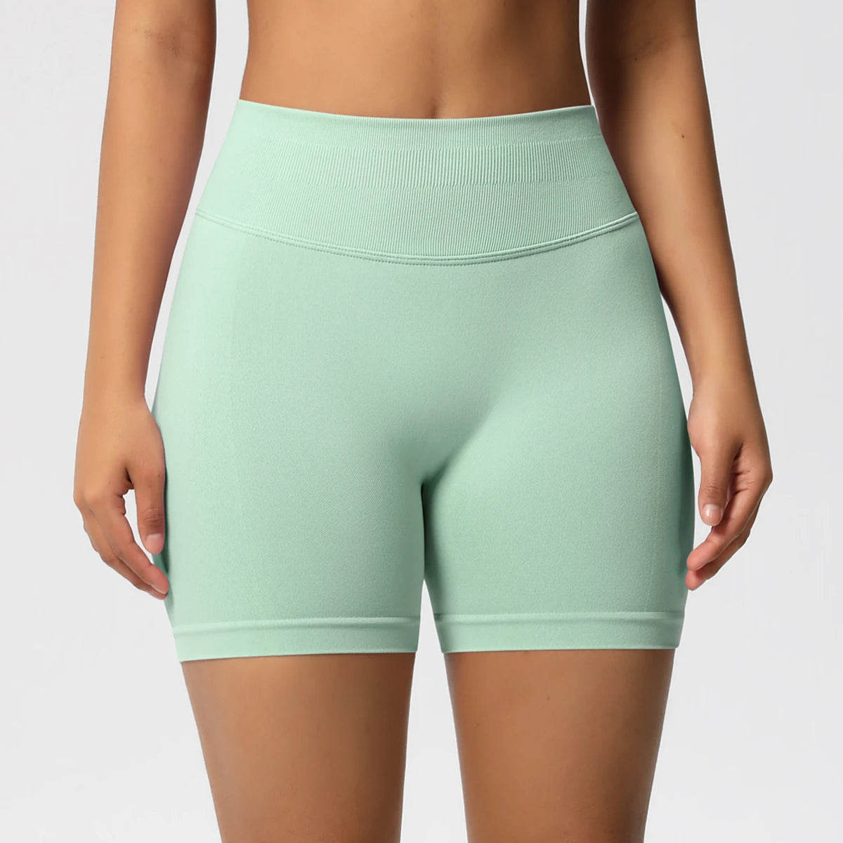 Hohe taillierte Sportshorts, hellgrün, eng geschnitten, mit breitem Bund vorne.