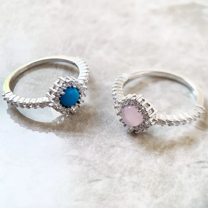 Silberne Ringe mit blauem und rosafarbenem Stein im Strahlenkranz, Pavé-Band