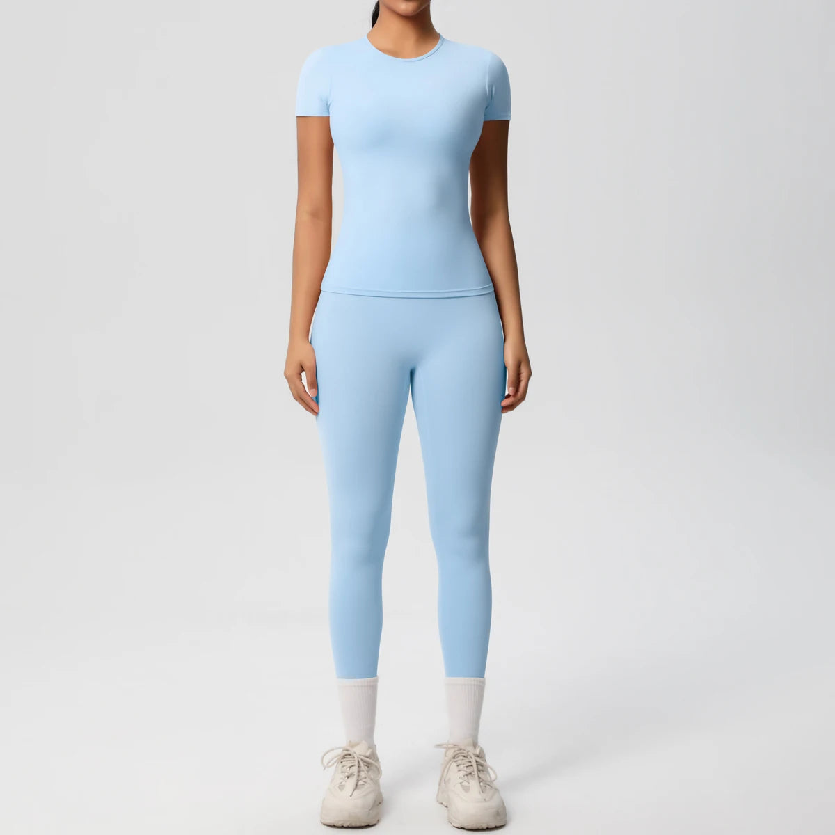Hellblaues Sport-Set mit Crop-Top und Leggings, enganliegend, 3/4-Länge, weißer Abschluss.