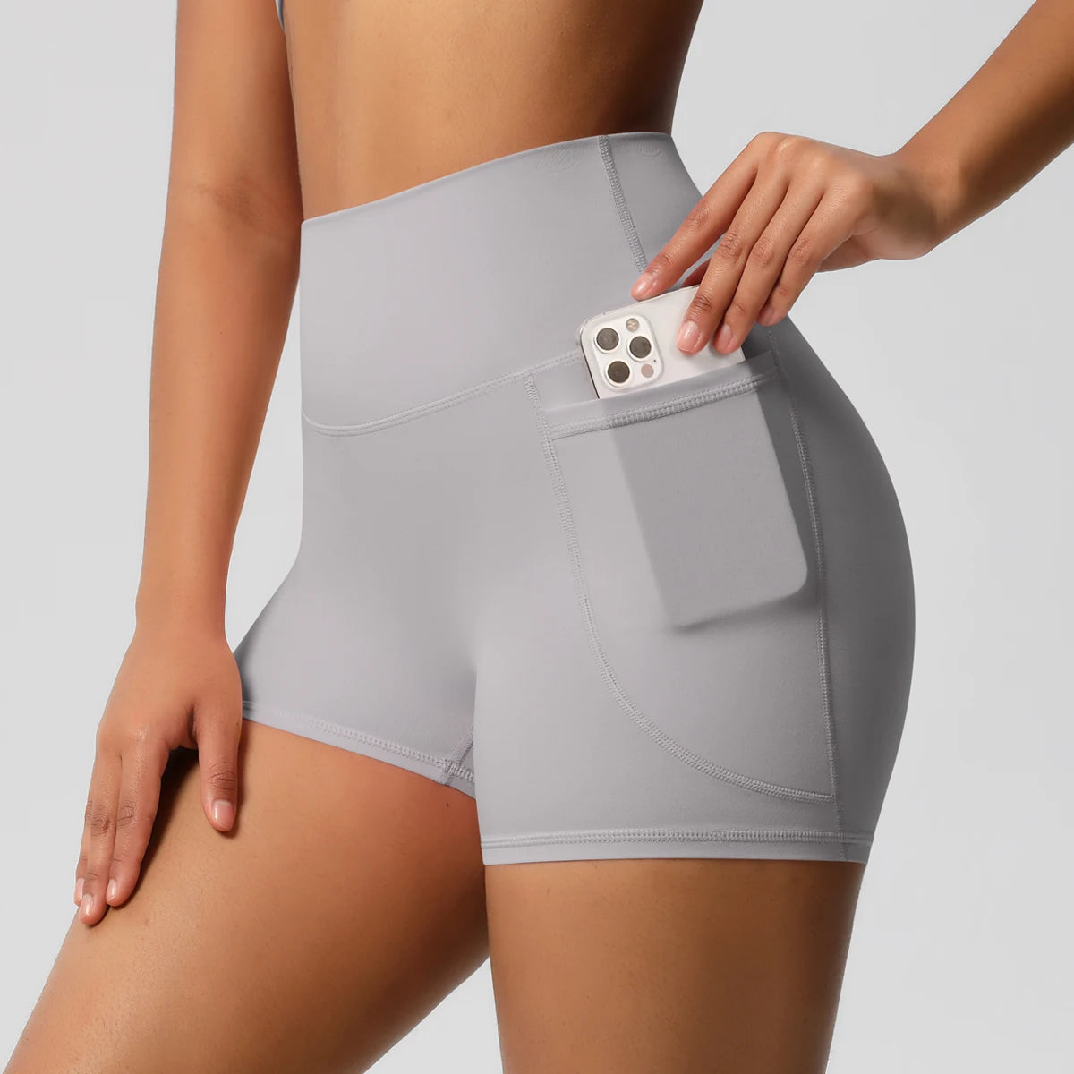 Damen-Yogashorts hohe Taille mit Seitentaschen, hellgrau, mit eingestecktem Handy